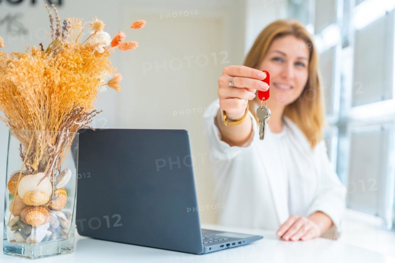 Focus on the hands of a happy female property agent handing over keys in the office