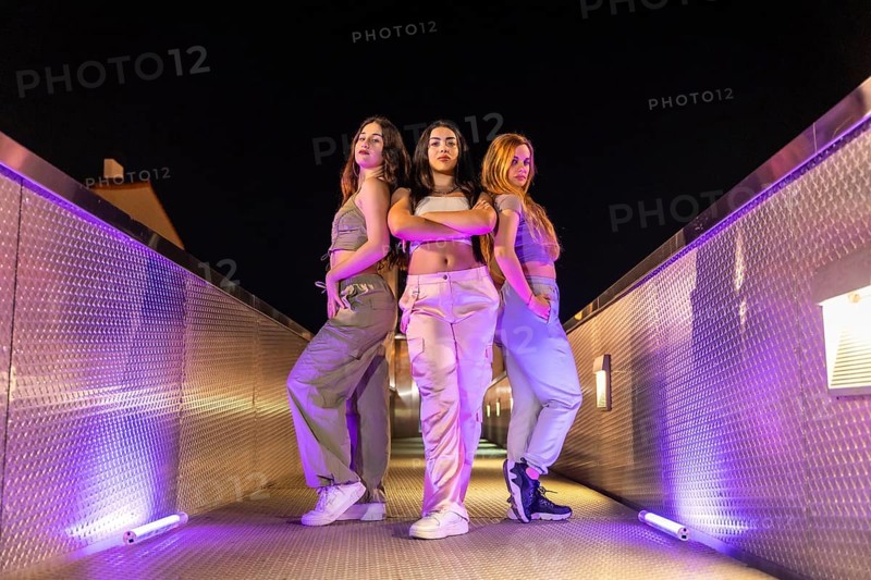 Low angle view portrait of a group of young female freestyle and hip hop dancers outdoors at night