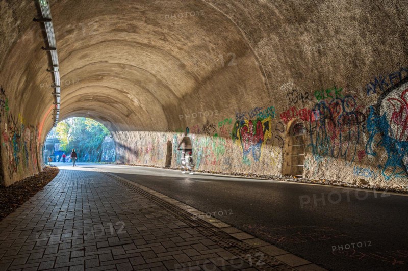 A cyclist rides through a graffiti tunnel with focussed lighting, Nordbahntrasse, Elberfeld, Wuppertal, Bergisches Land, North Rhine-Westphalia