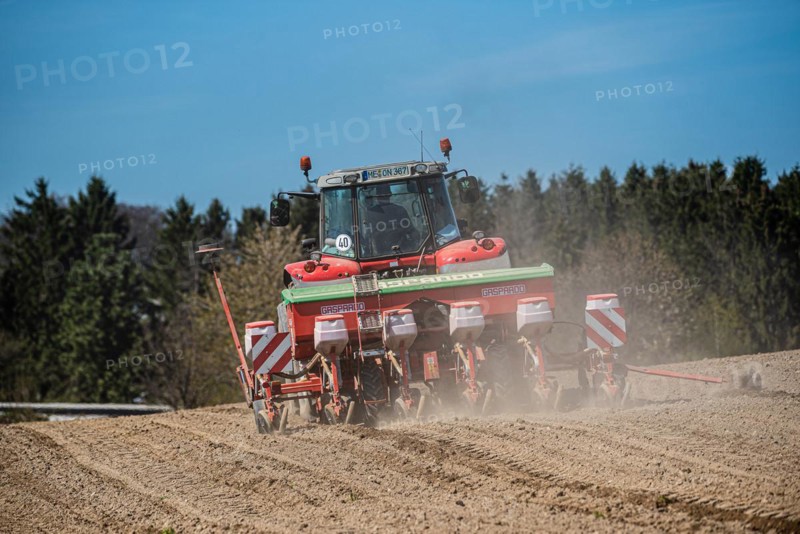 A tractor ploughs a field under a clear sky with swirling dust, Wuelfrath, Mettmann, North Rhine-Westphalia