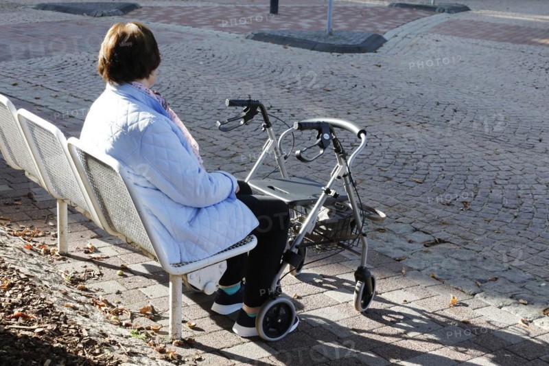 A pensioner sits on a bench, in front of her is a rollator, Bad Harzburg, 06.10.2018