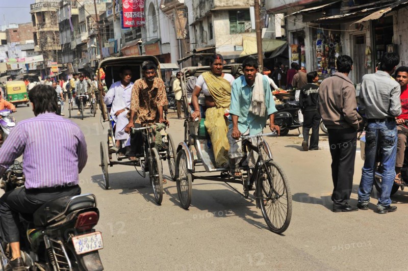 People travelling in cycle rickshaws on a busy street with shops, Varanasi, Uttar Pradesh, India, Asia