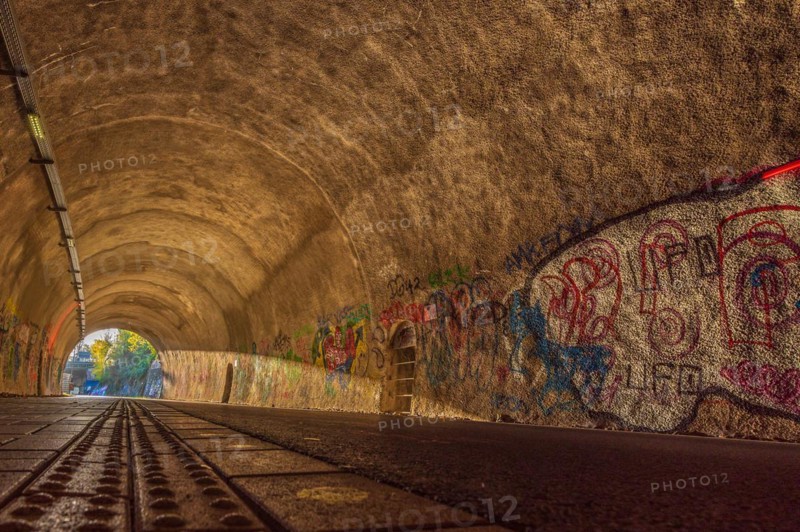 Cycle path through a tunnel with colourful graffiti on the walls and tracks on the floor, Nordbahntrasse, Elberfeld, Wuppertal, Bergisches Land, North Rhine-Westphalia