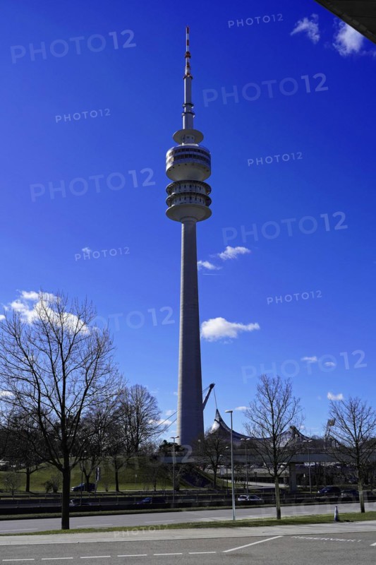 A tall television tower rises into the blue sky with trees in the foreground, BMW WELT, Munich, Germany, Europe