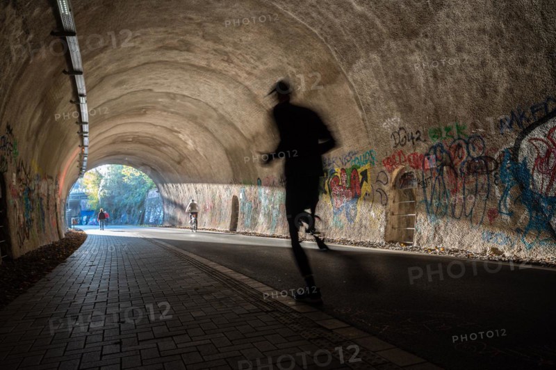 A jogger moves through a tunnel with graffiti and dynamic shadows, Nordbahntrasse, Elberfeld, Wuppertal, Bergisches Land, North Rhine-Westphalia
