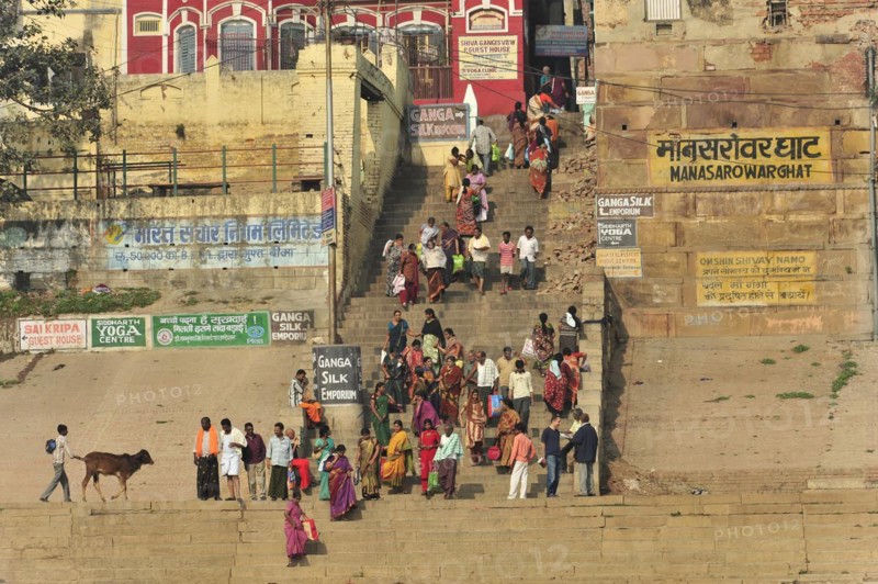 A group of people in traditional dress gather on a riverbank with yoga signs, Varanasi, Uttar Pradesh, India, Asia