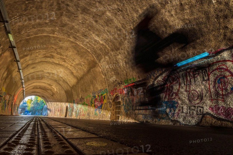 Blurred cyclist in a tunnel whose walls are covered with colourful graffiti, Nordbahntrasse, Elberfeld, Wuppertal, Bergisches Land, North Rhine-Westphalia