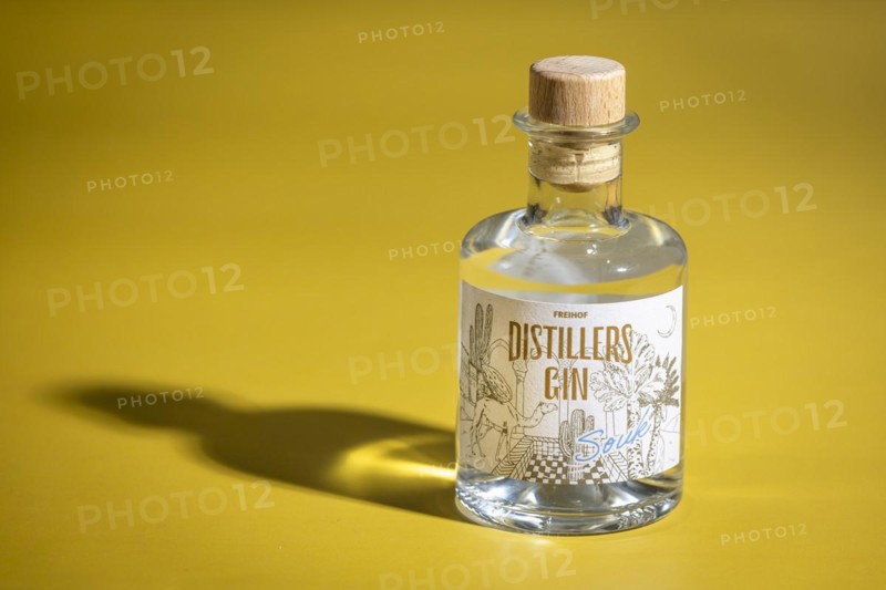 Bottle of gin on a yellow background with interesting shadows