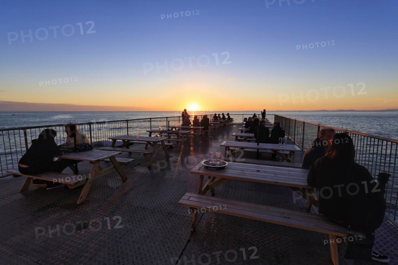 Tourists enjoying sunset on pleasure pier, Royal Pier, Cardigan Bay, Aberystwyth, Ceredigion, Wales, United Kingdom, Europe