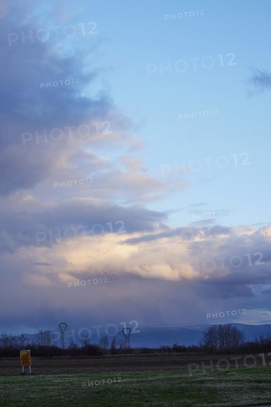 Weather change with mighty light to grey-blue clouds illuminated by the evening sun over the Black Forest as seen from Algolsheim, Haut-Rhin, Grand Est, France, Europe