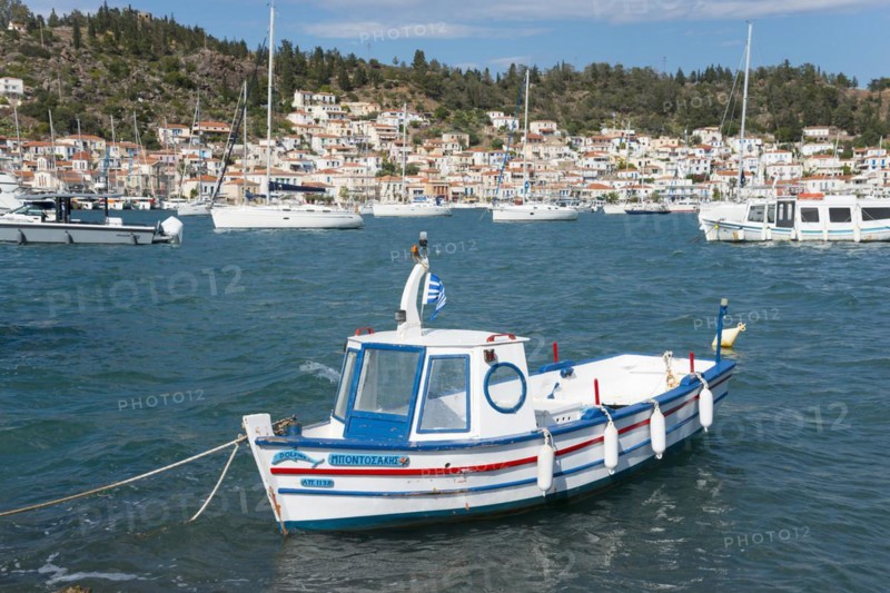 A moored boat in a quiet harbour with a view of sailing boats and white coastal houses, view from Galatas, Argolis, to Poros, Poros Island, Saronic Islands, Peloponnese, Greece, Europe