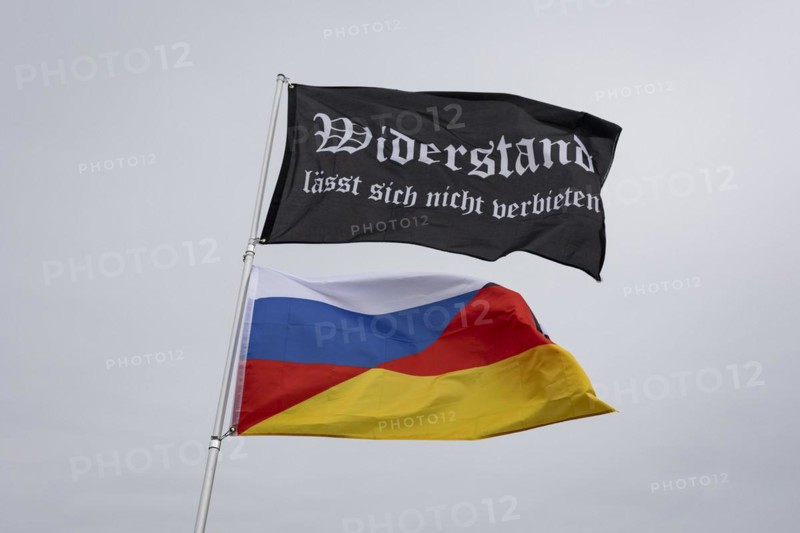 A waving flag with the inscription 'AeoeWiderstand laesst sich nicht verbieten'Aeo and a combination of German and Russian flags, taken during the 'AeoeBauern-Proteste'Aeo in Berlin, 22 March 2024