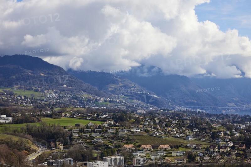 View of the outskirts of Vevey and mighty white spring clouds moving over mountains near Jongny, Jongny, Riviera-Pays-d'Enhaut district, Vaud, Switzerland, Europe