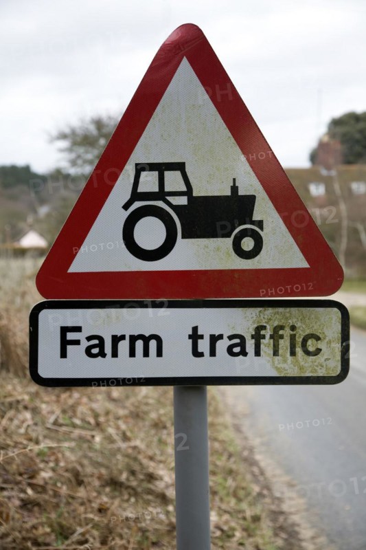 Red triangular road sign for farm traffic, UK