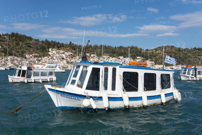 A small boat sways on the clear water of a picturesque harbour with a city view in the background, water taxi, view from Galatas, Argolis, to Poros, Poros Island, Saronic Islands, Peloponnese, Greece, Europe
