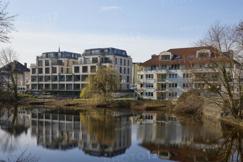 Residential and commercial buildings are reflected on the water surface of the swan pond in Minden, Muehlenkreis Minden-Luebbecke, North Rhine-Westphalia, Germany, Europe
