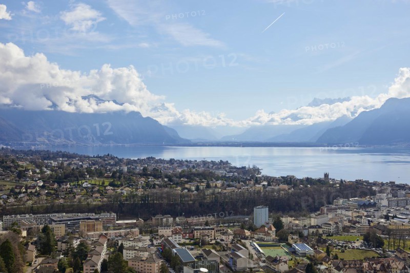 View of Vevey and Lake Geneva with cloudy, misty mountains in the background from Jongny, Riviera-Pays-d'Enhaut district, Vaud, Switzerland, Europe