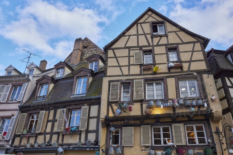 Facades of historic half-timbered houses decorated with watering cans in the old town centre of Colmar, Department Haut-Rhin, Grand Est, France, Europe