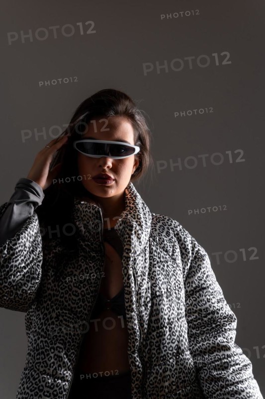 Studio portrait with grey background of a futuristic woman using mixing reality intelligent goggles