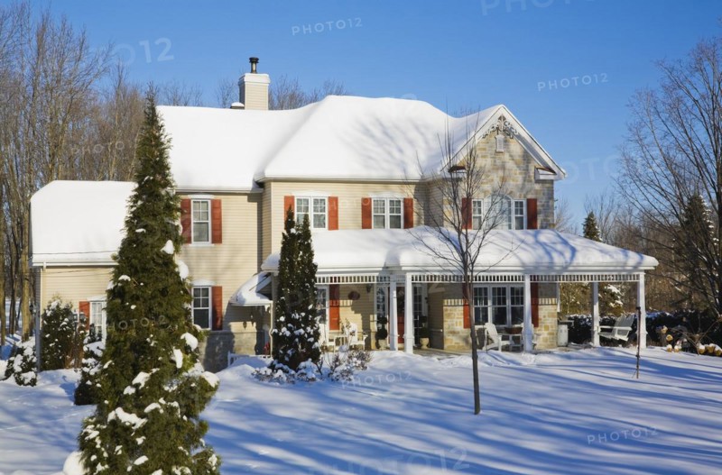 Two story beige vinyl siding with brownish red nuanced brick veneer and orange trim home in winter, Quebec, Canada, North America