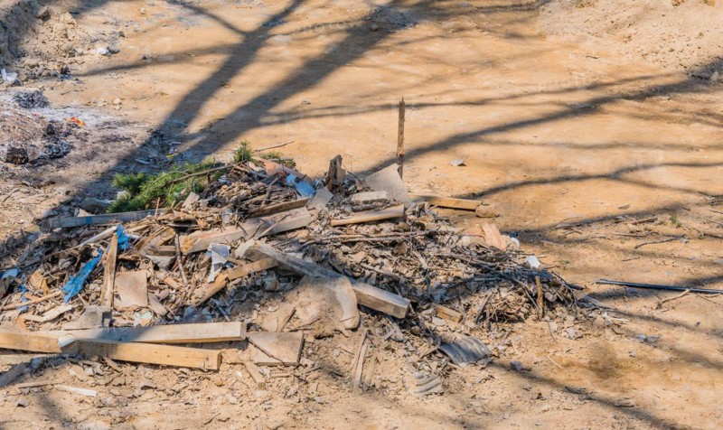 Pile of construction debris and wood scraps shadowed by a tree, in South Korea