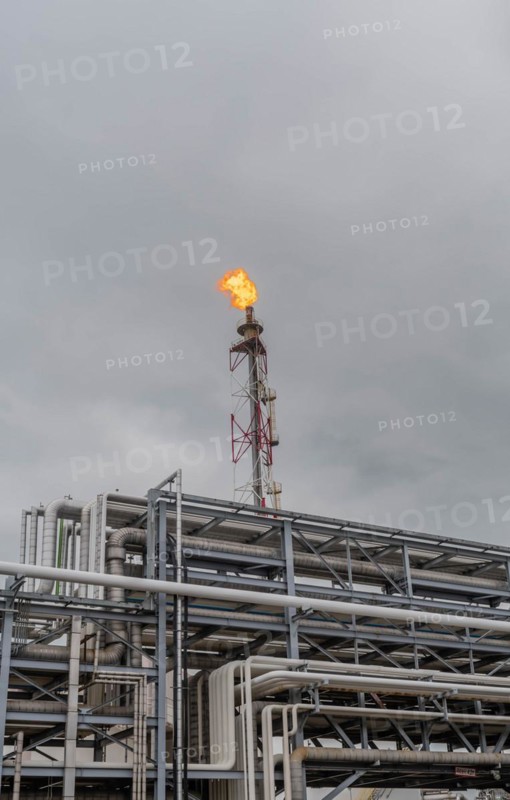 Fire atop a flare stack within a sprawling industrial facility under an overcast sky, in Ulsan, South Korea, Asia