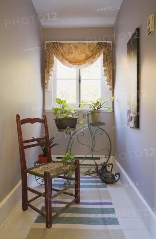 Antique wooden weaved seat chair and ornamental Penny-Farthing bicycle support stand for planters on upper floor hallway inside old 1877 home, Quebec, Canada, North America