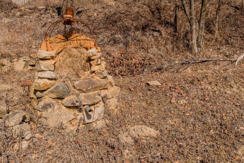 Stone structure with rusted wire frame and pipe sticking out of bottom in mountain park in Boeun, South Korea, Asia