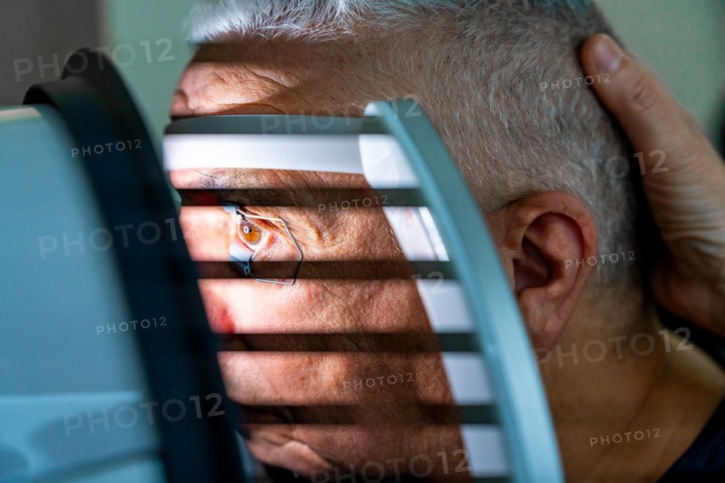 Close-up photo of a senior man receiving a laser treatment for glaucoma in a clinic