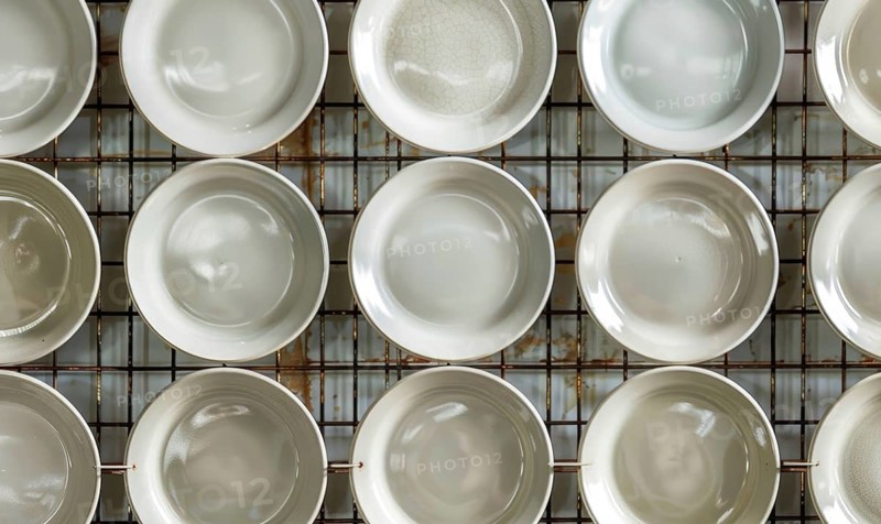 Overhead view of symmetrically arranged white plates on a clean kitchen rack AI generated