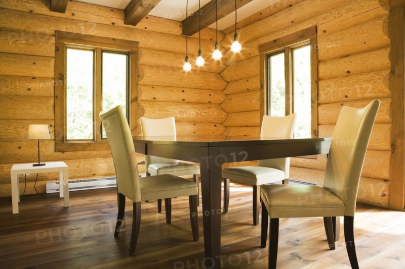 Brown wooden table and white cotton cloth upholstered high back chairs in dining room inside contemporary style log home, Quebec, Canada, North America