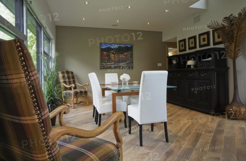 Clear glass top table and white leather high back chairs in dining room with beige ceramic tile floor inside modern cubist style home, Quebec, Canada, North America