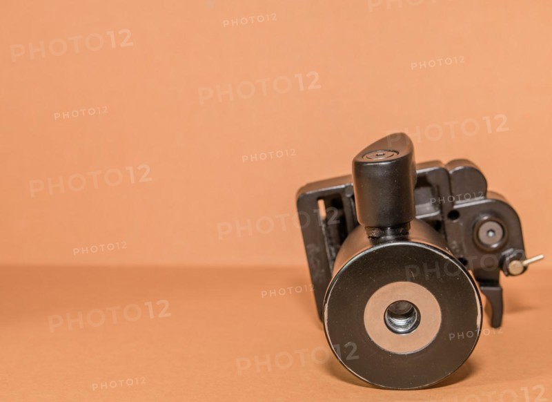 Closeup bottom view of quick release tripod head on brown background. Selective focus on thread for mounting
