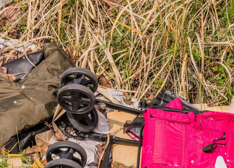 Discarded luggage and a baby stroller among debris on grass, in South Korea