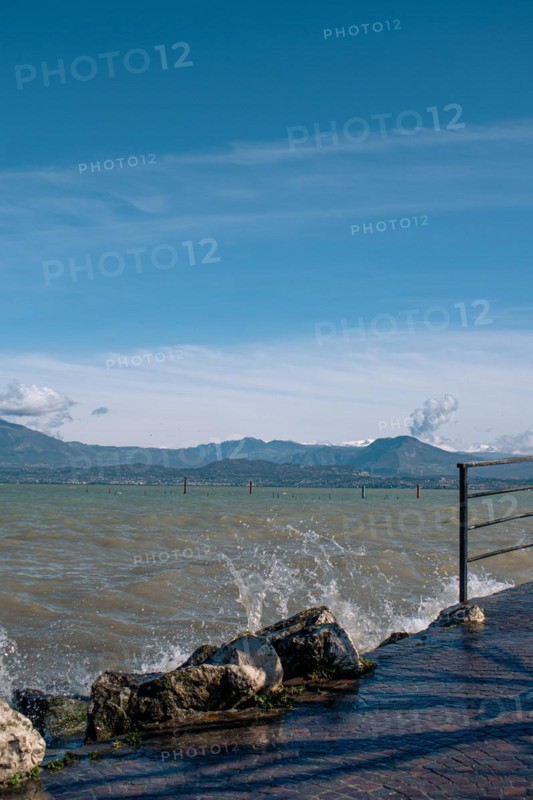 Splashing waves hitting rocks on the shore of Lake Garda, Sirmione, Lake Garda, Italy, Europe