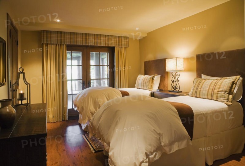 Guest bedroom with single beds and wooden dresser in basement inside luxurious log cabin home, Quebec, Canada, North America