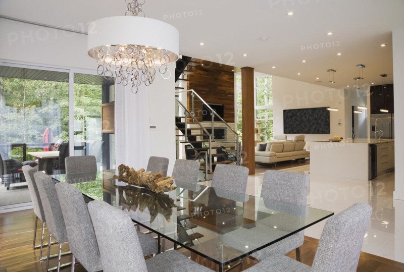 Glass dining table with gray upholstered high back chairs in dining room inside luxurious home, Quebec, Canada, North America