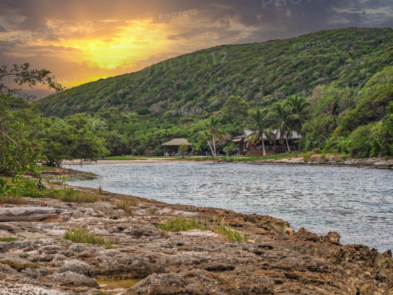 Rocky coast, long bay by the sea at sunset. Dangerous view of the Caribbean Sea. Tropical climate at sunset in La Porte d'Enfer, Grande Terre, Guadeloupe, French Antilles, North America