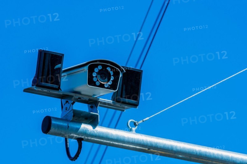 Closeup of closed circuit camera mounted on metal pole against light blue sky in background in South Korea