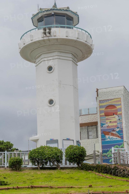 White lighthouse with a beacon on top, surrounded by trees and a wall mural, in Ulsan, South Korea, Asia