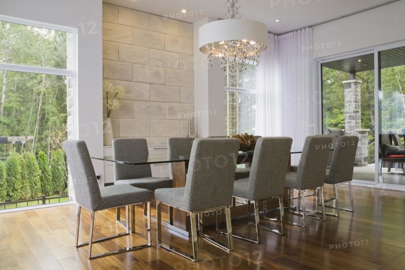 Glass dining table with gray upholstered high back chairs in dining room inside luxurious home, Quebec, Canada, North America