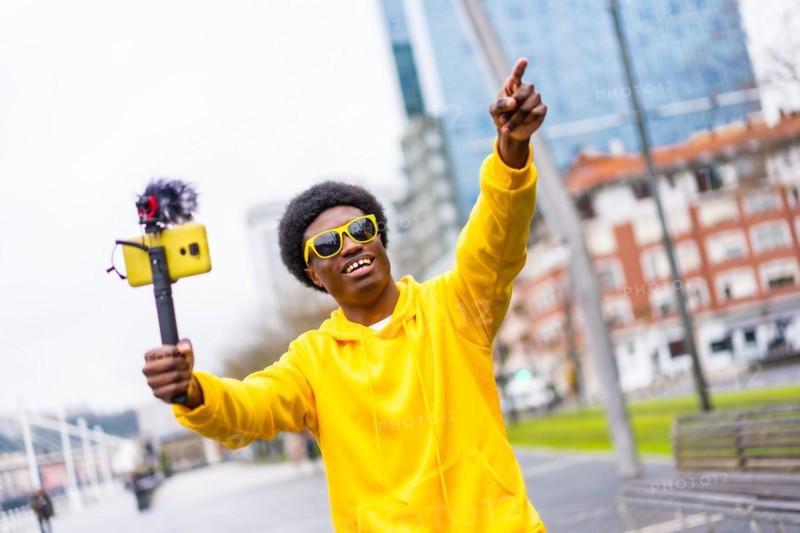 African cool young vlogger pointing ahead during a live streaming in the city