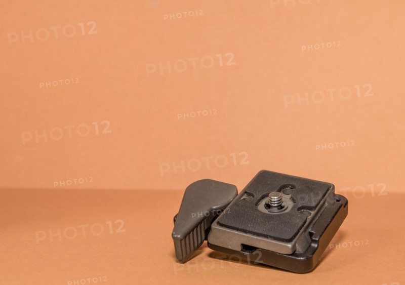 Closeup top view of quick release tripod head on brown background