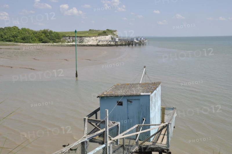 Wooden hut and walkway on a tranquil beach with low tide under a clear blue sky, fishery in Talmon