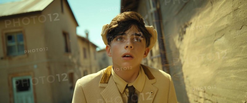 A young boy in vintage attire looks cautiously around a corner in a sunlit old town, AI generated