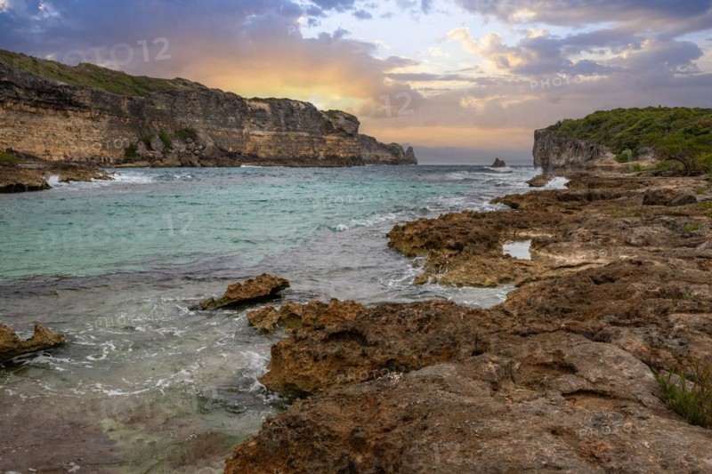 Rocky coast, long bay by the sea at sunset. Dangerous view of the Caribbean Sea. Tropical climate at sunset in La Porte d'Enfer, Grande Terre, Guadeloupe, French Antilles, North America