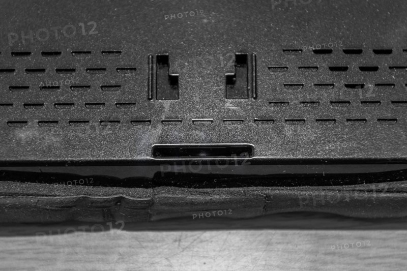 Closeup of holes of mounting plate and speaker in back of car navigation system
