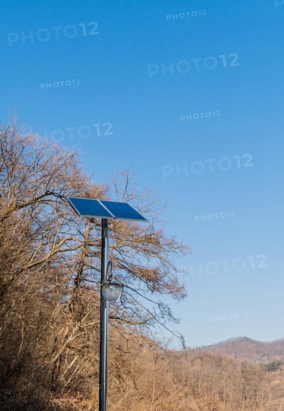 Small solar panel on top of chrome pole in front of leafless trees against blue sky in Buan, South Korea, Asia