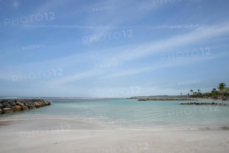 Caribbean dream beach with palm trees, white sandy beach and turquoise-coloured, crystal-clear water in the sea. Shallow bay on a cloudy day. Plage de Sainte Anne, Grande Terre, Guadeloupe, French Antilles, North America