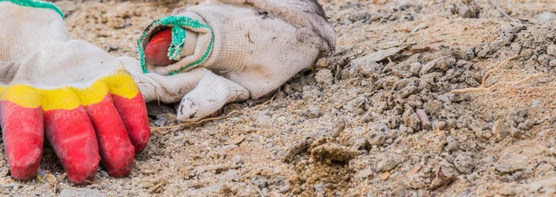 Worn work gloves discarded among construction debris and dirt, in South Korea